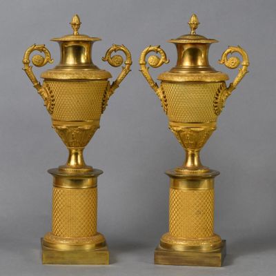 une paire de vases anciens en laiton sur socles, sur fond gris