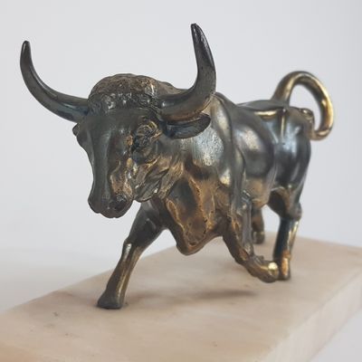 statue d'un taureau posée sur un socle en marbre, sur fond blanc