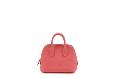 the small pink bag is sitting on a white surface