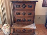 a wooden chest of drawers in a room with a vase on top of it