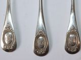 three spoons and a fork are sitting on a white surface