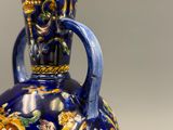 un vase bleu et jaune muni d'une anse, posé sur une table