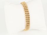 a close up of a gold chain bracelet on a white pillow