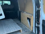 à l'arrière d'une camionnette dont la porte est ouverte et où se trouve une table
