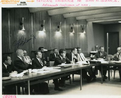 plusieurs hommes assis à une longue table dans une salle de réunion