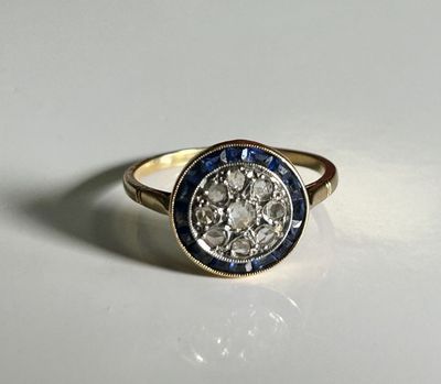 a close up of a diamond and sapphire ring on a white surface