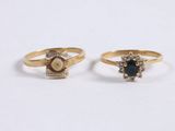 two gold rings with sapphire and diamonds on a white surface