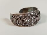 a close up of a silver bracelet on a white surface