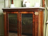 une vitrine en bois avec des portes vitrées et une étagère sur laquelle sont posés des vases