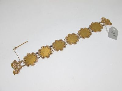 a close up of a gold bracelet on a white surface
