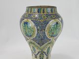 a blue and green vase sitting on a white surface