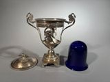 a silver vase and a blue bell on a table