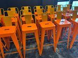 rows of orange metal stools in a room with a blue carpet