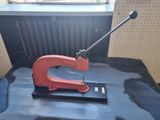 une photo d'une agrafeuse rouge et noire posée sur une feuille bleue