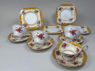 cinq tasses, deux soucoupes et une assiette sur la table