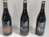 three bottles of wine are lined up on a white surface