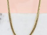 un gros plan d'un collier en or posé sur une surface en marbre