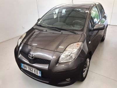 une Toyota Yaris noire garée dans une pièce blanche