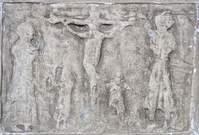 relief of a crucifidus on a stone wall with a man on the cross