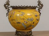 un vase jaune orné de fleurs, posé sur une table