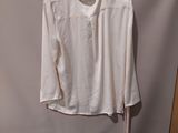 white shirt hanging on a hanger in front of a white backdrop