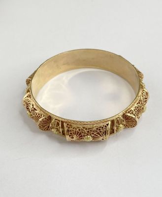 gros plan d'un bracelet en or sur une surface blanche
