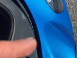 le doigt d'une personne pointant vers la poignée de porte d'une voiture bleue