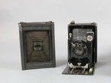 two old cameras sitting next to each other on a white surface