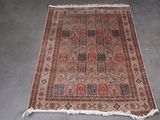 un tapis persan ancien aux motifs rouges et bleus sur un fond gris
