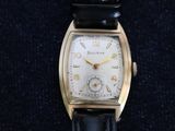 an image of a gold watch with a black leather strap