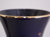 a close up of a blue vase with a gold rim