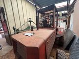 a red table with a lamp on top of it in a warehouse