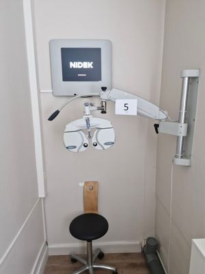 an image of a medical room with a monitor and a chair