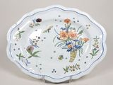 une assiette décorée de fleurs, posée sur un socle
