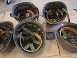 six military helmets sitting on top of a cardboard box on a table