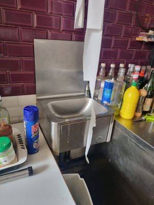 un évier de cuisine avec de nombreuses bouteilles posées sur le plan de travail