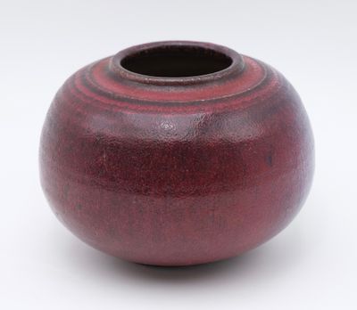 a red vase that is sitting on a white surface