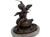 bronze statue of a woman sitting on a rock with a sword in her hand