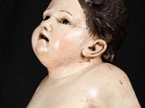 a small statue of a baby sitting on a black surface