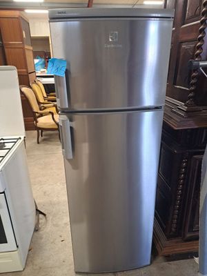 a silver refrigerator in the middle of a room next to a stove