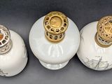 three white vases with gold decorations on them on a table