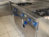 a large stainless steel kitchen with a stove and oven