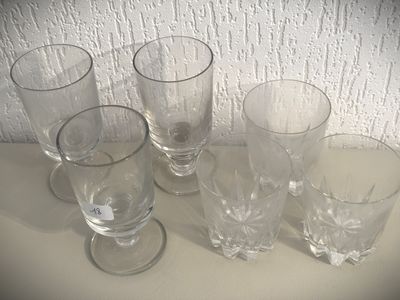 cinq verres posés sur une table, avec un mur blanc en arrière-plan