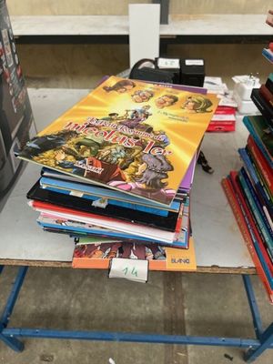 beaucoup de livres posés sur une table, avec une télévision en arrière-plan