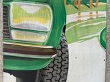 a poster of a green car on the side of the road