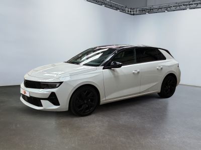 La voiture blanche est garée dans une grande pièce aux murs blancs.