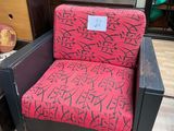 une chaise rouge et noire ornée d'un motif de graffiti, placée devant un miroir