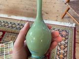 a person holding a green vase in their hand