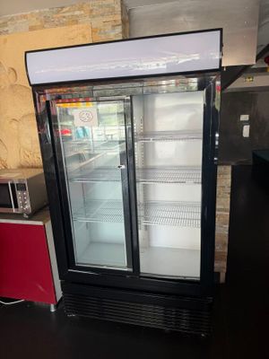 a refrigerator with two glass doors and a microwave on the counter