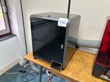 une imprimante 3D posée sur une table près d'une fenêtre